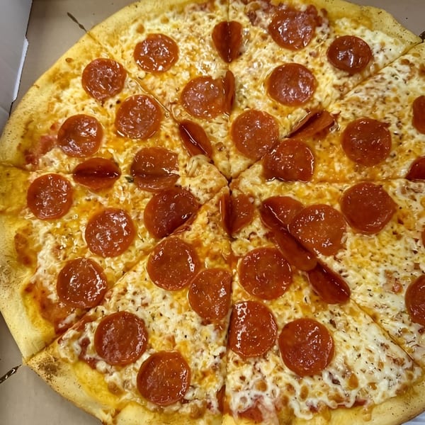 A whole pepperoni pizza with melted cheese and a golden crust, sliced and ready to eat.